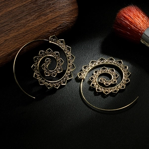 Detail view of retro gold spiral hoop earrings with intricate hollow floral patterns