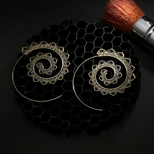 Detailed view of vintage gold spiral earrings with intricate floral relief on a dark base