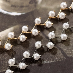 Detail von elegantem Gold- und Silberschmuck in Astform mit weißen Perlen auf dunklem Grund