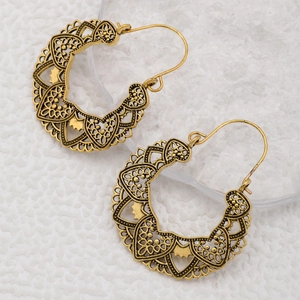 Detail of vintage bronze circular earrings with intricate bohemian hollow geometric patterns