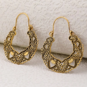 Detailed view of vintage hollow-out metal earrings in antique gold with boho floral patterns