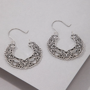 Close-up of bohemian silver metal hollow flower pattern hoop earrings with intricate details