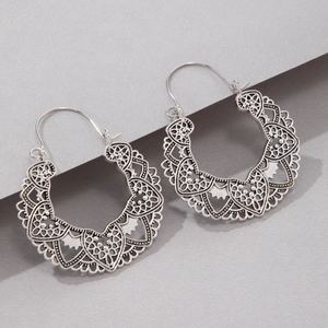 Detail of vintage silver hollow floral earrings with intricate bohemian lace pattern