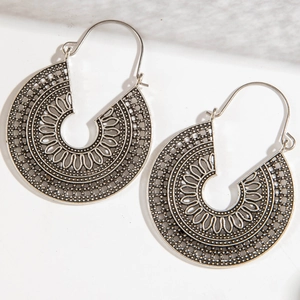 Detailed macro view of bohemian silver metal earrings with intricate hollow patterns