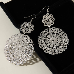Macro detail of vintage silver hollow mandala earrings with intricate filigree texture