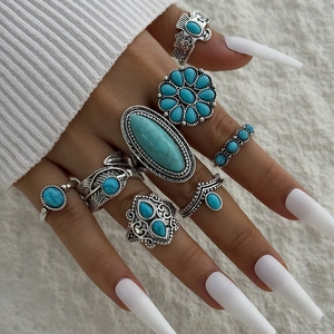 Close-up of Bohemian silver ring set with turquoise stones worn by model on white fabric