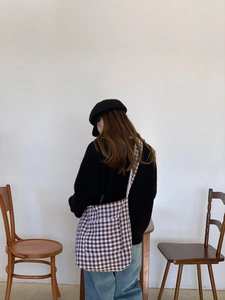 Rear view of a model wearing the brown gingham canvas tote bag with a wide strap