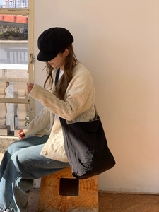 Detail of a black large capacity canvas crossbody bag with side pocket and minimalist design