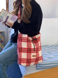 Detail of red and white plaid lamb wool tote bag with drawstring and leather star label