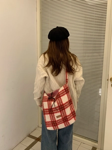 Detailed view of red plaid sherpa shoulder bag featuring a drawstring closure and bow