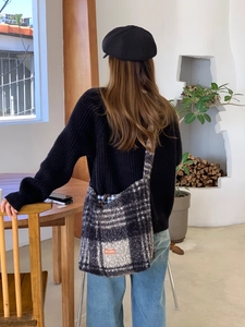 Detail of grey plaid faux shearling bag featuring a signature orange leather patch