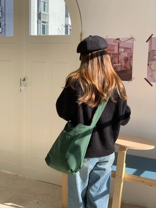 Detail view of the large dark green canvas tote bag showing the wide shoulder strap and fit