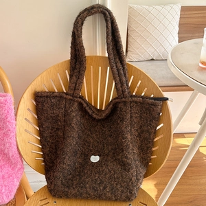 Sac fourre-tout en fausse fourrure marron avec logo sur une chaise design chic