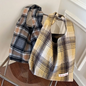 Detail of wool plaid tote bag with On Our Way embroidery on modern acrylic chair