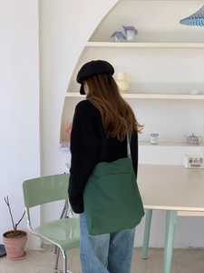 Detail view of large dark green plaid fleece shoulder bag on a model in minimalist style
