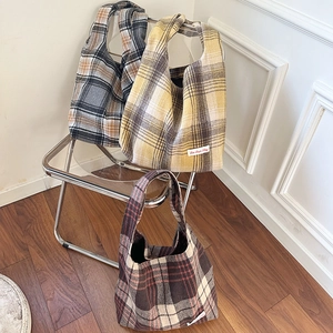Detailed view of three wool plaid tote bags in various autumn colors with letter patches