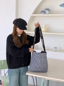 Blue and white gingham tote bag with long grey straps shown in a cozy indoor setting