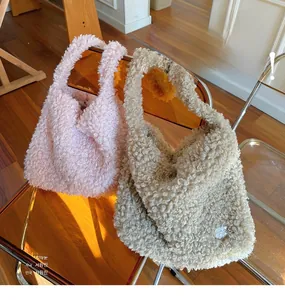 Détail de sacs cabas en polaire peluche rose et beige avec texture douce sur une chaise