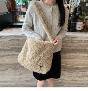 Vue latérale du sac bandoulière en fausse fourrure beige assorti à un pull en maille grise