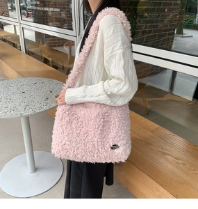 Détail du sac à bandoulière en fausse laine rose avec texture douce et décor métallique