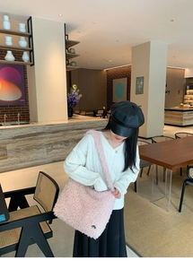 Sac à épaule rose en polaire bouclée dans un café avec une tenue d'automne décontractée