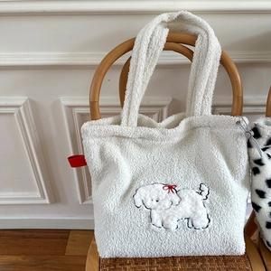 Close-up of white plush tote bag with dog embroidery hanging on a wooden chair