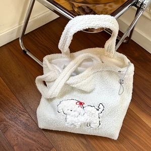 Detail of white faux fur tote bag featuring embroidered puppy with red bow and drawstring