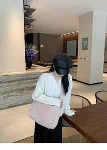 Détail de la texture d'un grand sac cabas rose en fausse fourrure avec plaque métal