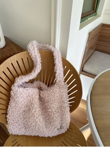 Détail d'un sac cabas en polaire rose effet mouton posé sur une chaise en bois