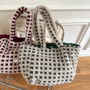 Close-up of plush checkerboard tote bag featuring metal logo and magnetic closure detail