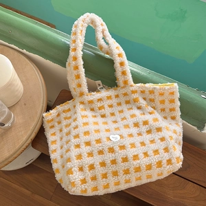 Close-up of yellow and white plush checkerboard tote bag with heart metal emblem