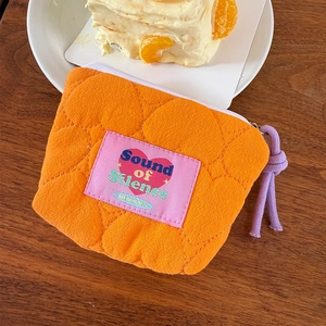 Dettaglio di una mini pochette trapuntata arancione con motivi a cuore e zip colorata