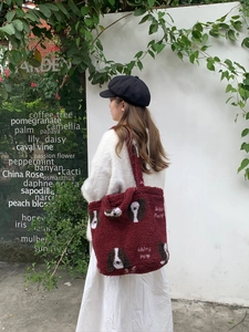 Outdoor shot of a burgundy faux shearling tote bag with a cute cartoon dog pattern