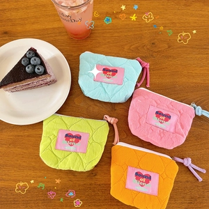 Pochette quadrate trapuntate in colori pastello su un tavolo di legno con decorazioni
