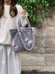 Detail of grey plush bucket bag featuring dalmatian print and a red ribbon accent