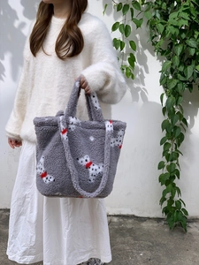 Detail view of grey plush bucket bag with dalmatian pattern and red bow decoration
