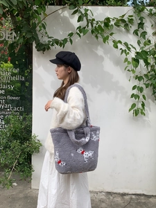 Detail of gray plush tote bag with dalmatian pattern worn over the shoulder by a model