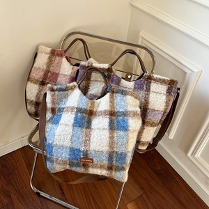 Close-up of plush plaid tote bags in various colors on a chair for autumn winter style