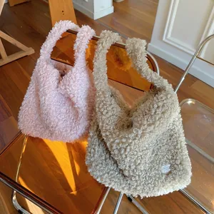 Sac cabas en polaire bouclée rose et beige posé sur une chaise moderne