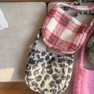 Detail of plush lamb wool plaid crossbody bags featuring leopard print and snap closure