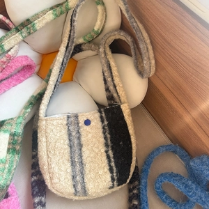 Detail of lamb wool plaid crossbody bag featuring stripe texture and blue button closure