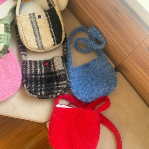 Detailed texture of assorted colorful fuzzy lamb wool plaid crossbody bags on a soft seat
