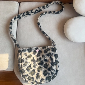 Detailed close-up of leopard pattern faux fur texture and pink snap button on crossbody bag
