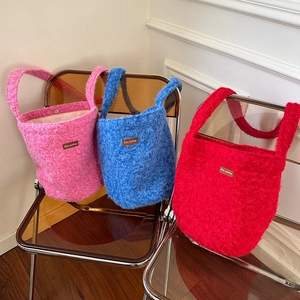 Close-up of colorful plush bucket bags in pink, blue, and red with soft fuzzy texture