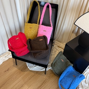 Detailed view of plush faux fur shoulder bags in six vibrant colors on a vintage chair