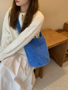 Close-up of blue fuzzy knit bucket bag with long plush texture worn by a model