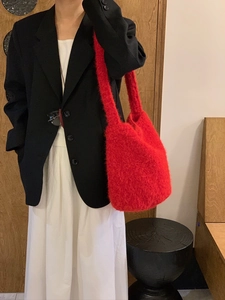 Close-up of fluffy red plush shoulder bag texture on model with black suit