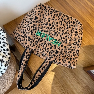 Detailaufnahme der Leoparden-Plüschtasche mit grüner Healer-Stickerei und Metallverschluss