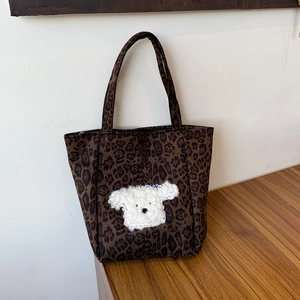 Detail of leopard print tote bag with cute white plush puppy embroidery and blue bow