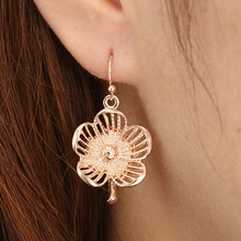 Nahaufnahme von Bohemian Hohlblumen-Ohrhängern in Roségold an einem weiblichen Model